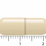 En beige kapsel af Vitakruid – Bufret Vitamin C® (90 veganske kapsler) er vist ved siden af en lineal, der måler cirka 2 centimeter i længden.