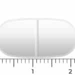 En hvid, oval Vitakruid Magnesium 200 Complex® tablet (90 tabletter), med en central delekærv, er vist ved siden af en lineal og måler omkring 2 centimeter i længden.