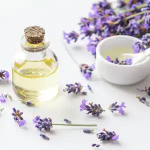 En 100 ml flaske OsiMagnesium – Good Night Melatonin Body Lotion med en propprop, omgivet af lavendelkviste. En hvid skål med væske og en ske er i baggrunden.